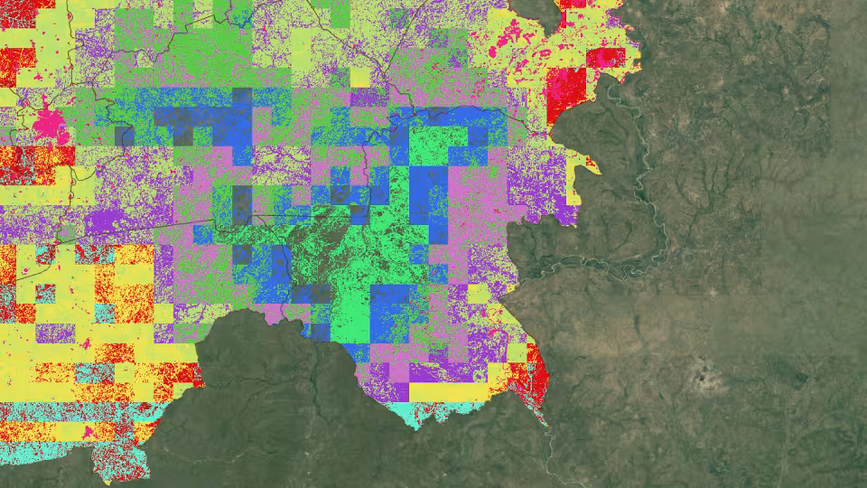 Satellite map overlay with pixelated grid data in red, yellow, green, purple, and blue tones depicting land cover or remote sensing analytics.